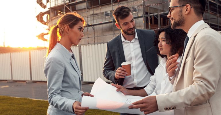 Business people discussing a blueprint in front of the construct