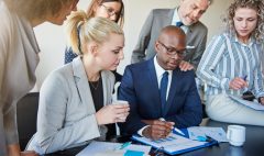 Diverse group of executives discussing paperwork around a boardroom table