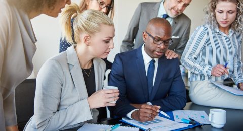 Diverse group of executives discussing paperwork around a boardroom table