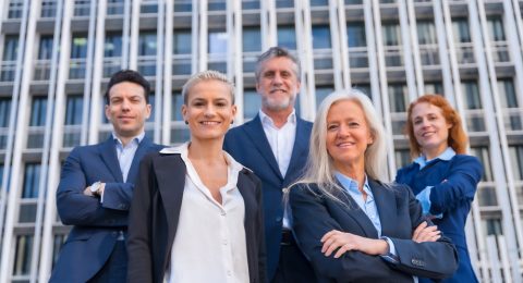 Group of confident business professionals posing in front of a modern building