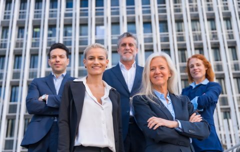 Group of confident business professionals posing in front of a modern building