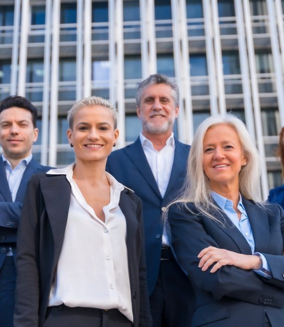 Group of confident business professionals posing in front of a modern building