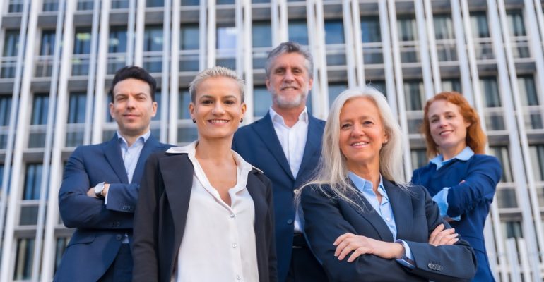 Group of confident business professionals posing in front of a modern building