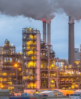 Chemical plant at dusk with lights and smoke