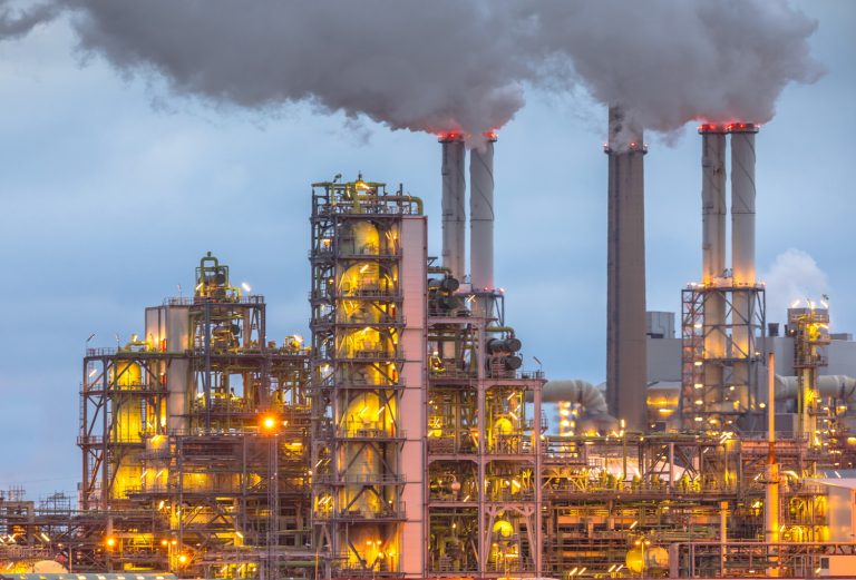 Chemical plant at dusk with lights and smoke